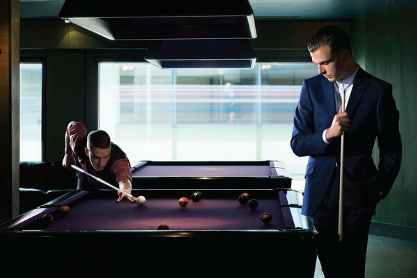 Les hommes en costumes jouent au billard