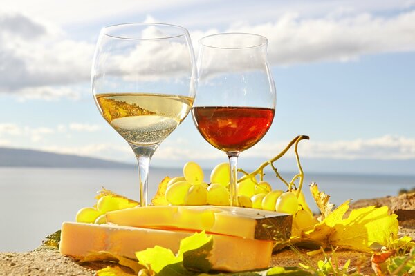 Still life with glasses of red and white wine on the background of the sea