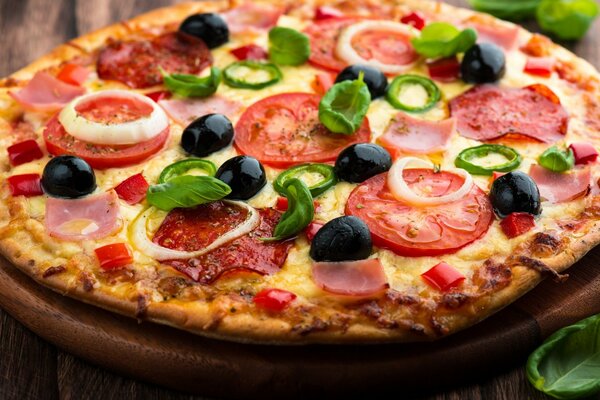 Pizza on a board with tomatoes, cheese, olives and onions