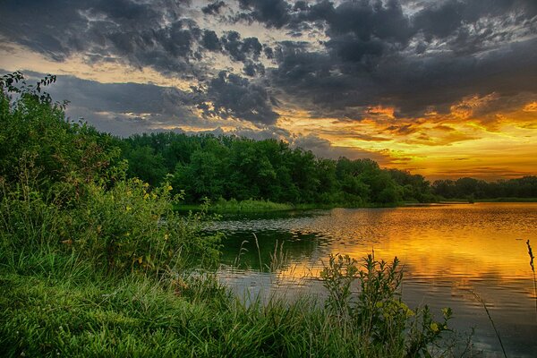 Summer sunset with clouds on the background of the lake