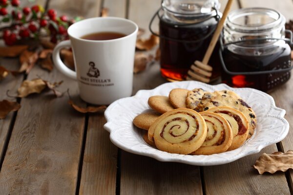 Tee In einer weißen Tasse mit Keksen und Honig auf einem Holztisch