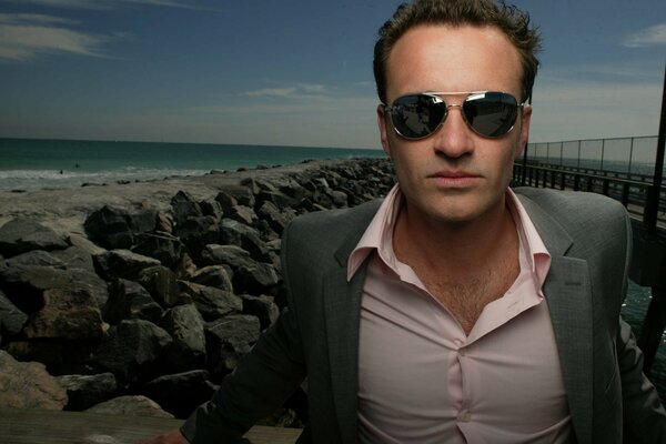 Julian McMahon on the background of a rocky seashore