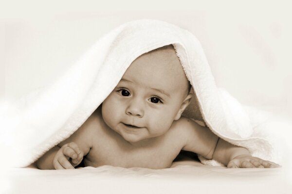 Ребенок в полотенце лежит улыбается