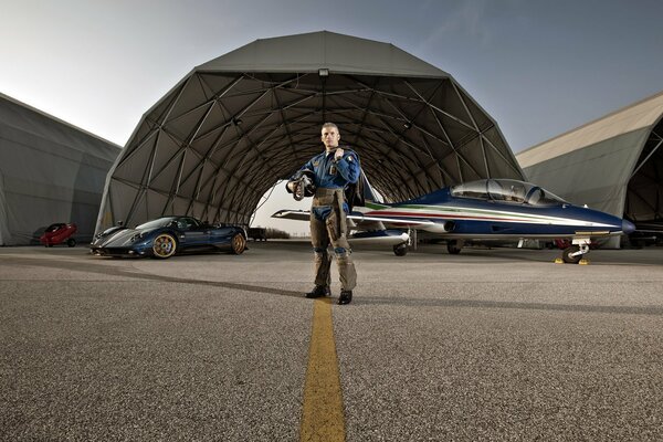 Pilot im Hintergrund eines Flugzeugs und eines Sportwagen