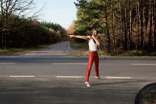 Freddie Mercury canta en la carretera. Bosque en el fondo