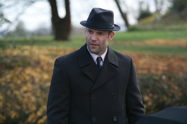 Jason Statham dans un chapeau et un manteau