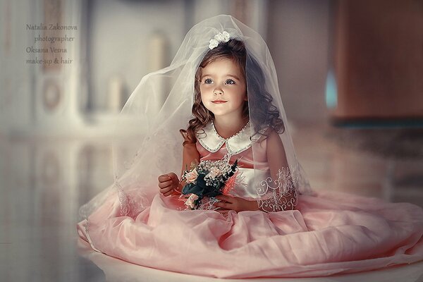 Petite fille en tenue de mariée. Bébé avec bouquet