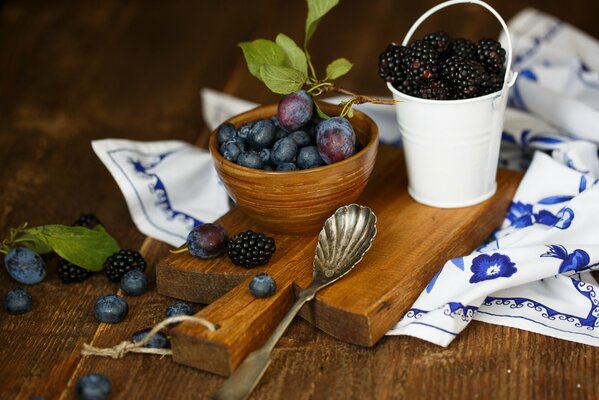 Plum with blueberries and blackberries on a wooden board