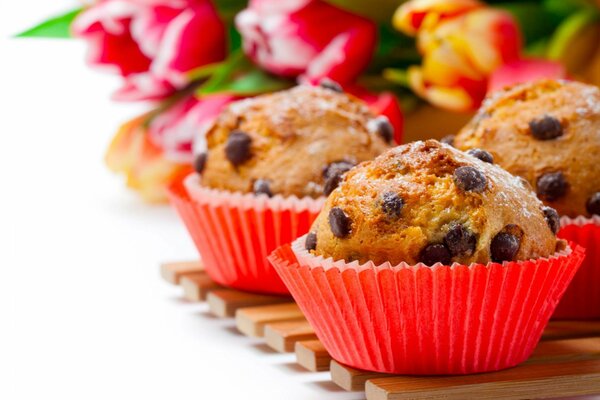 Cupcakes con chocolate en el fondo de un ramo de flores