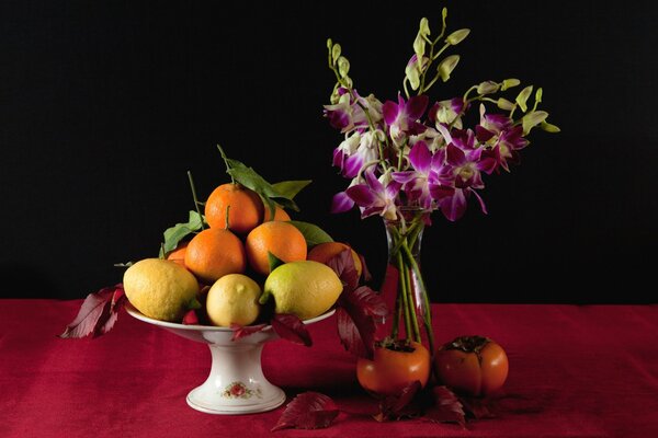 Ciotola con frutta e fiori in piedi accanto