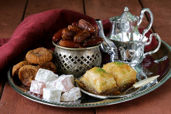 Sweets are on a tray next to a silver teapot and a cup