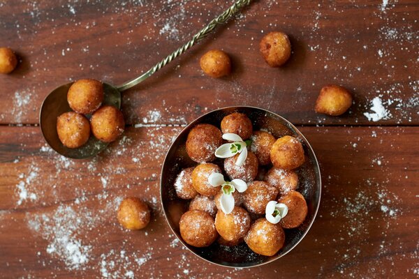 Beignets sur une table en bois saupoudrés de sucre en poudre