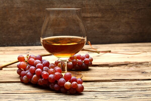 Ein Glas Cognac und ein Haufen Trauben auf dem Tisch