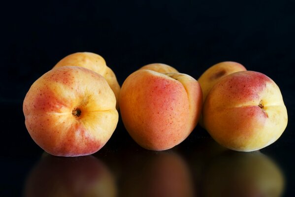 Apricots are reflected on a black background