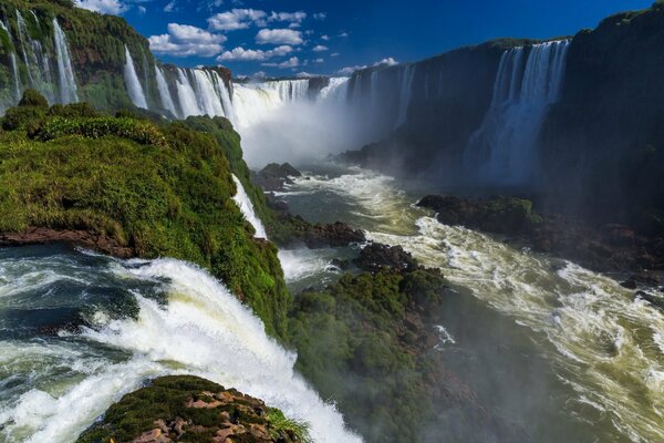 Contra el cielo una cascada tropical con una nube de salpicaduras