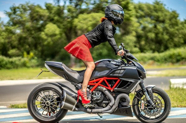 Chica en falda, tacones y casco en una motocicleta