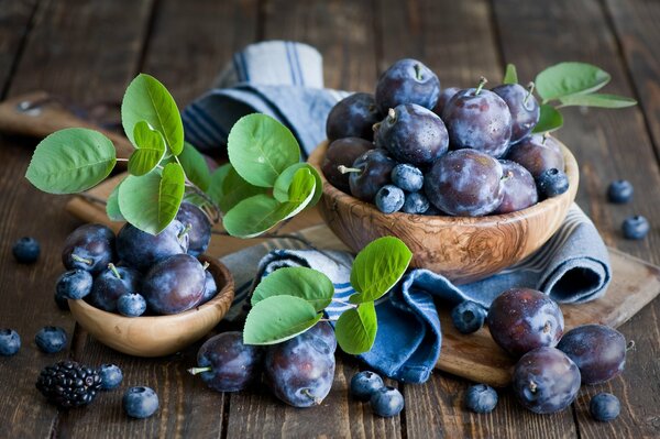 Blueberries and plums in wooden plates