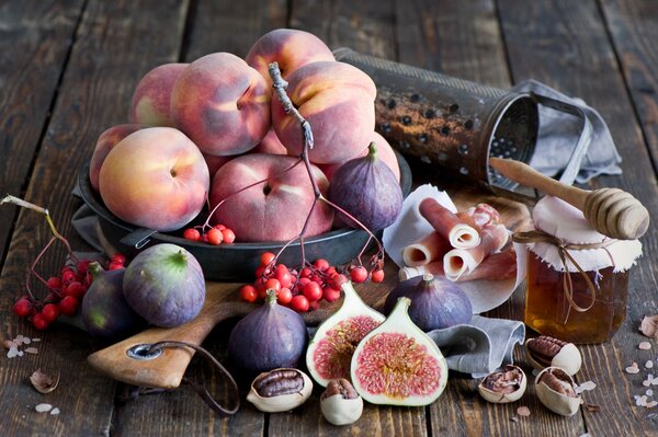 Autumn still life with the image of peaches, figs, honey and nuts