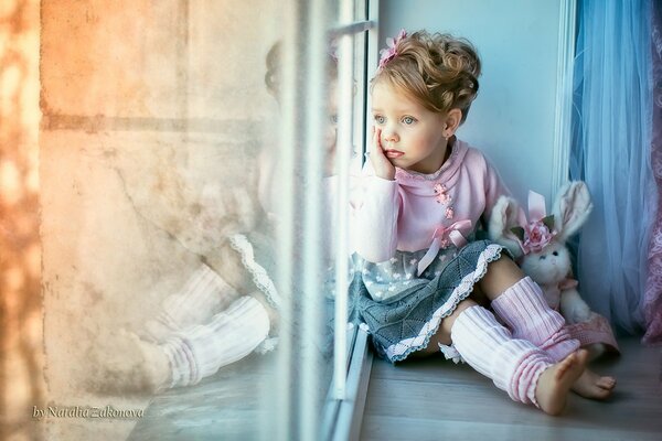 Милая девочка на окне с игрушкой трогательная