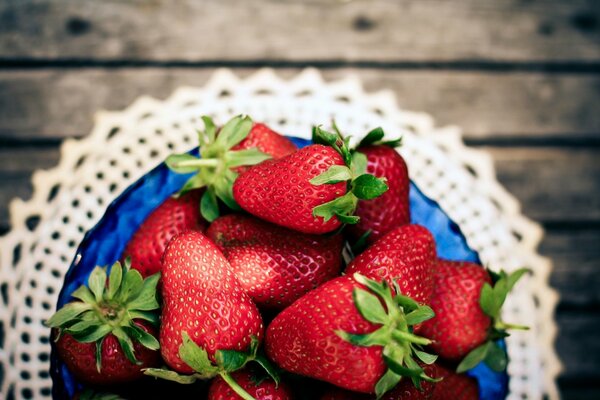 Fresas en un cuenco azul en una servilleta de encaje