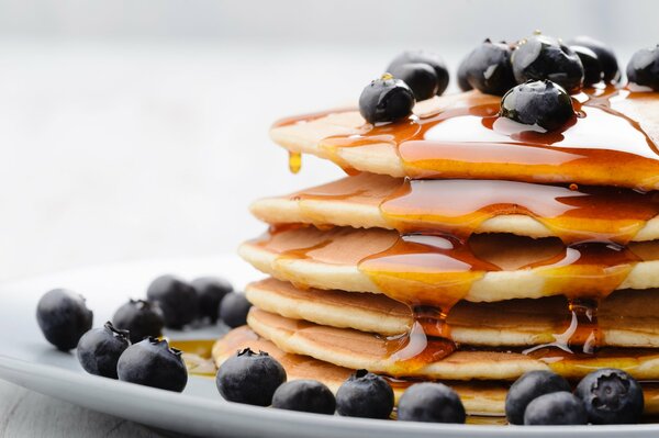 Pfannkuchen auf einem Teller mit Honig und Blaubeeren