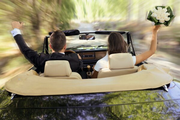 Ein Mann im Anzug und ein Mädchen mit einem Blumenstrauß rasten auf einem Cabrio