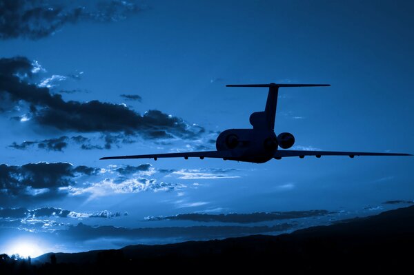 L avion vole dans le ciel nocturne au coucher du soleil