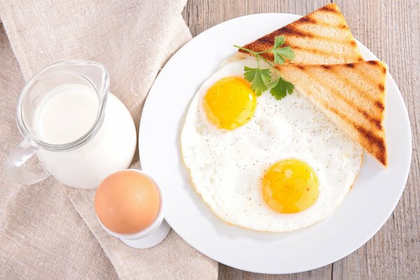 Desayuno con huevos revueltos, tostadas y leche