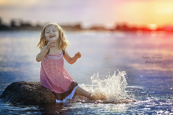 La ragazza schizza sulla riva. Tramonto sull acqua