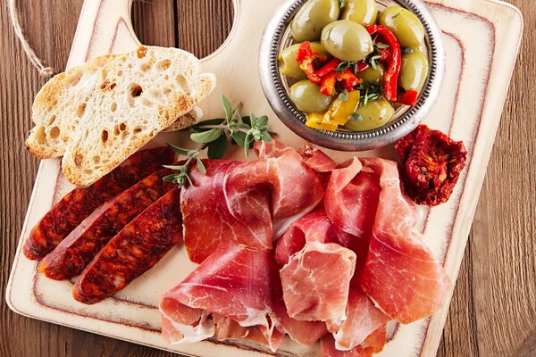 Meat products and vegetables with bread on a wooden board