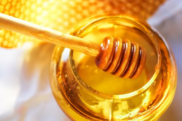 A jar of honey with honeycombs and a spoon