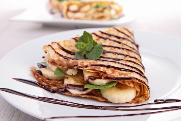 Pancake with banana and chocolate, decorated with mint leaf for dessert