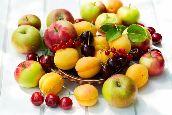 Fruits et baies sur la table: abricots, pommes, cerises, baies