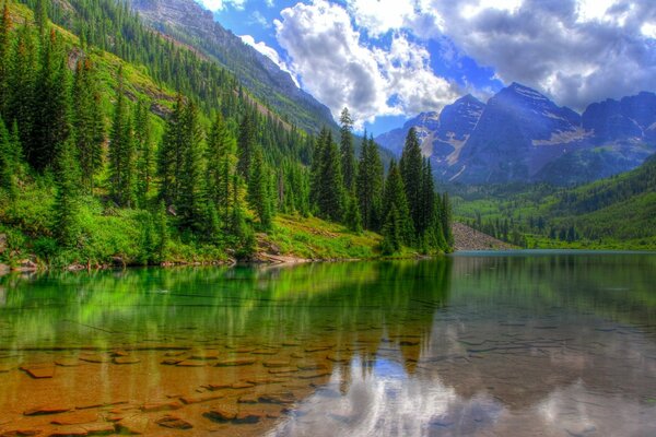 Un lago de montaña limpio con un fondo rocoso refleja las nubes