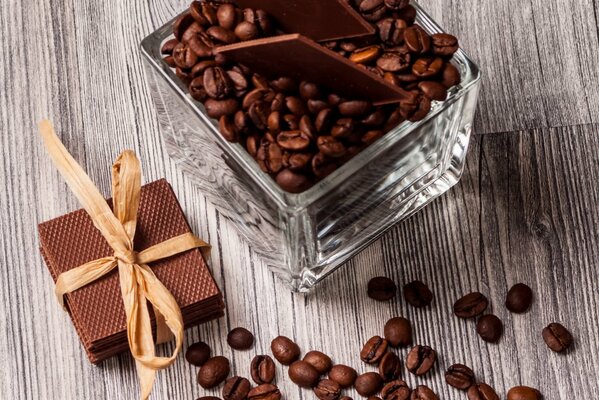 Кофейные зёрна и стопка из плиток шоколада, перевязанных ленточкой