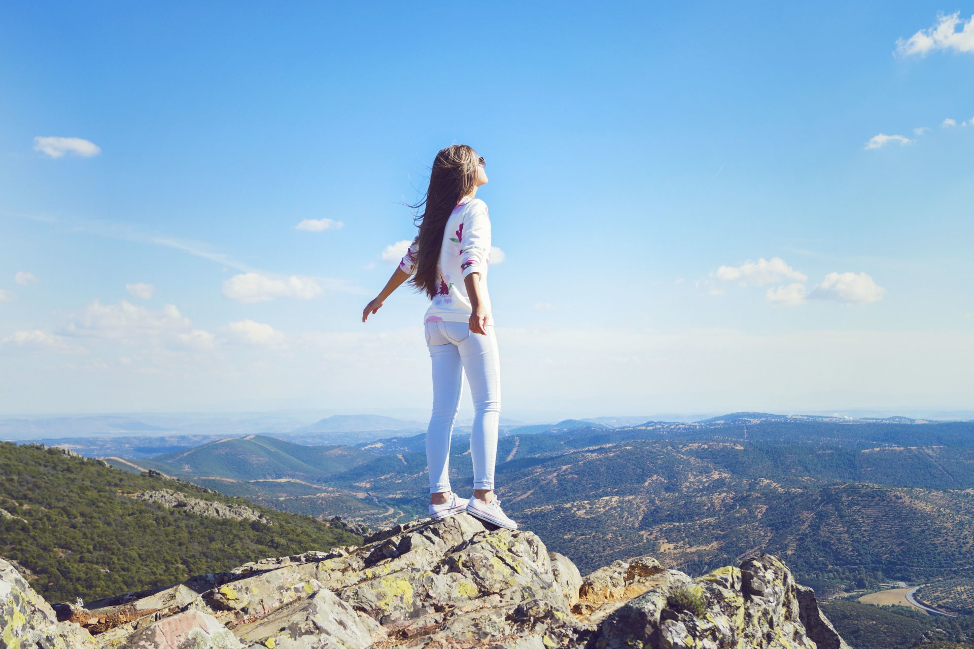 chica montaña jeans viento pelo pose de pie horizonte cielo nubes