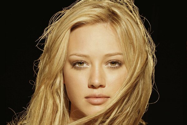 Portrait of Hilary Duff with a straight look on a dark background