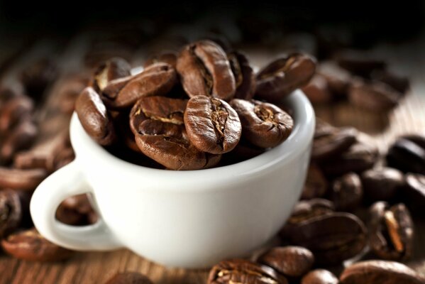 A cup of coffee beans stands on a wooden table