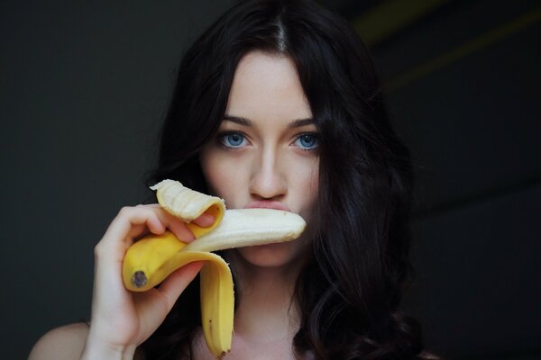 Blauäugige schöne Brünette isst eine Banane