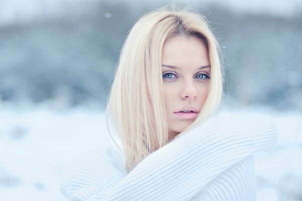 Blondine im weißen Pullover auf Schnee Hintergrund