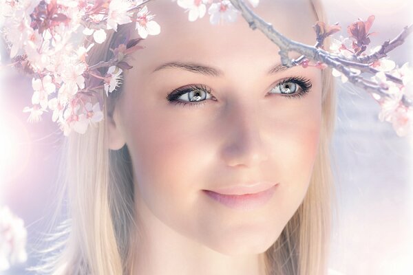 La cara de una niña con una sonrisa en el fondo de la floración de primavera