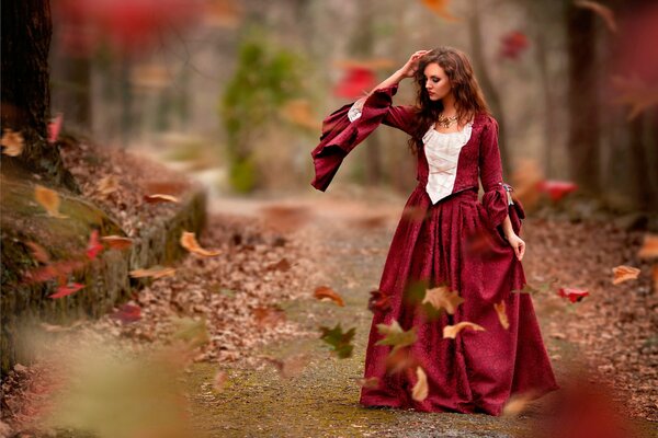 Mysterious girl in a red dress in autumn