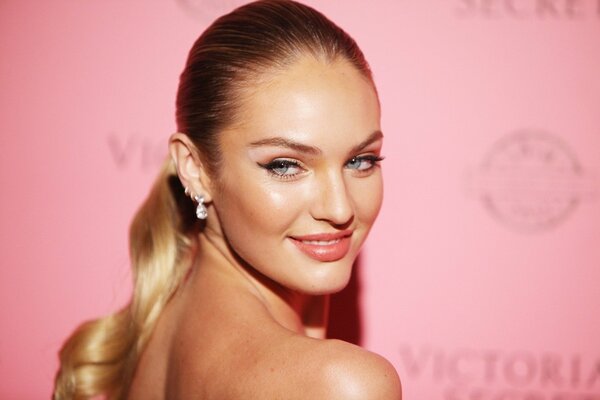 Blonde girl posing for a photo on a pink background