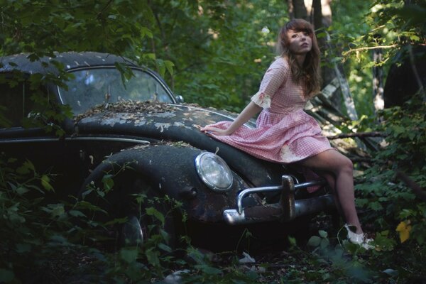 Chica romántica en un coche retro abandonado en el bosque