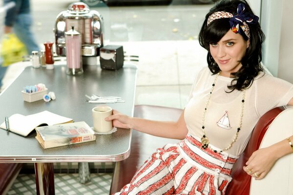 Ketty Perry Lee un libro con una taza de café