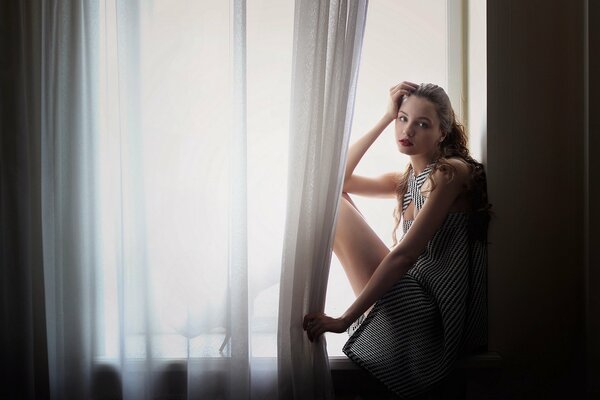 Beautiful girl with red lipstick by the window