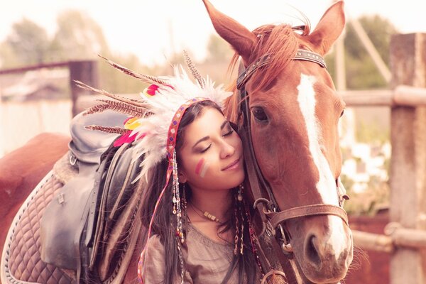 The girl stands and smiles at the fence with a horse