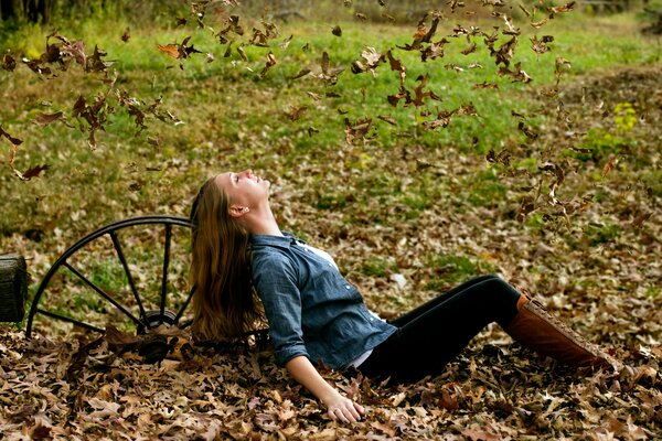 A girl is sitting on fallen leaves