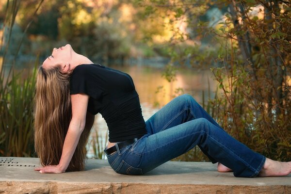 Girl in jeans by the lake with a thin waist