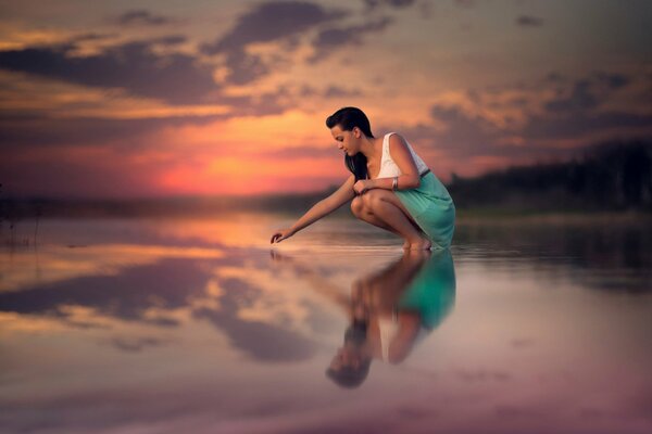 Jeune fille touche la surface de l eau du lac au coucher du soleil